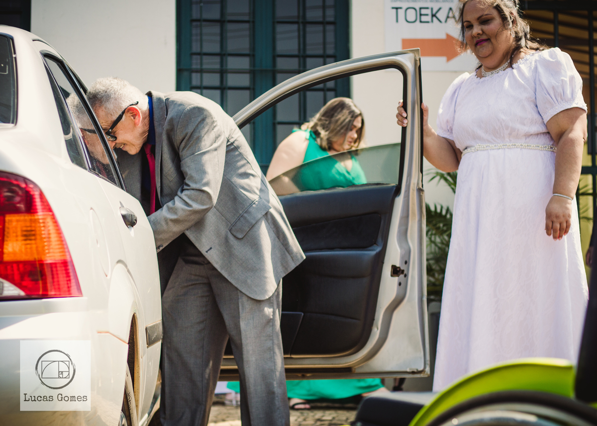 Pai do noivo pegando o noivo enquanto sua noiva segura a porta do carro
