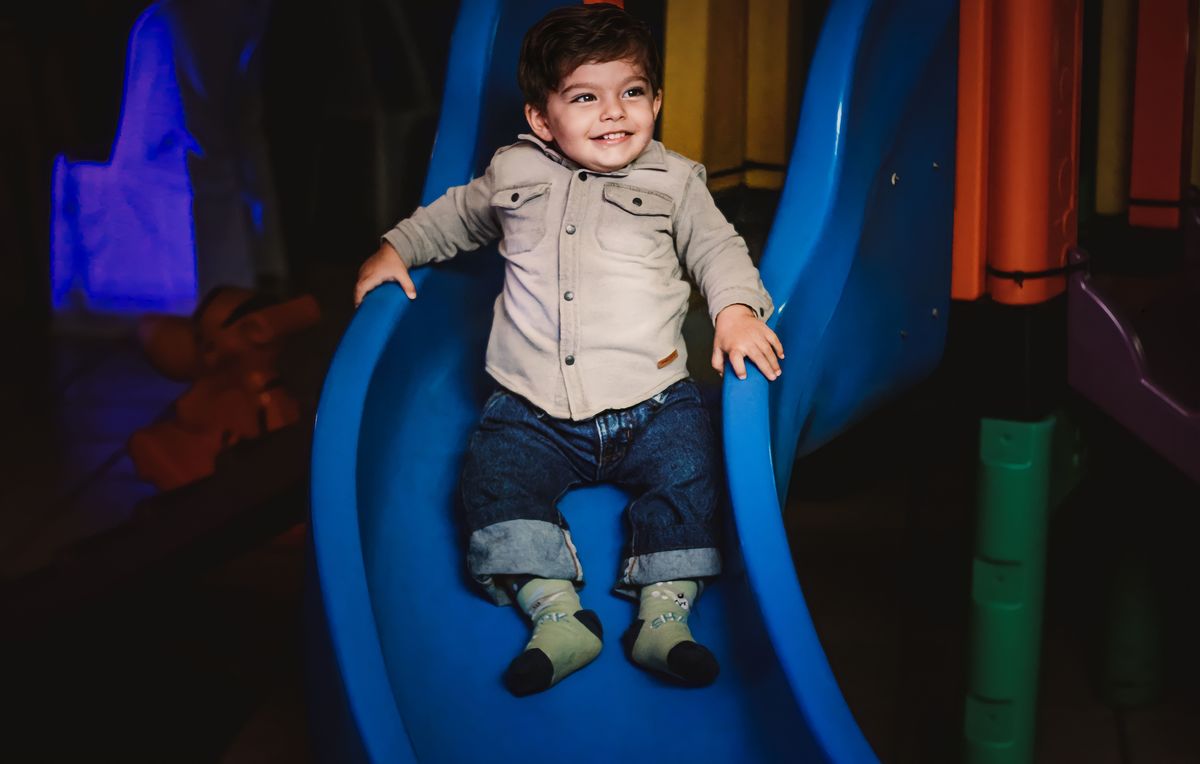 Fotografia deCriança sorrindo ao descer no escorregador