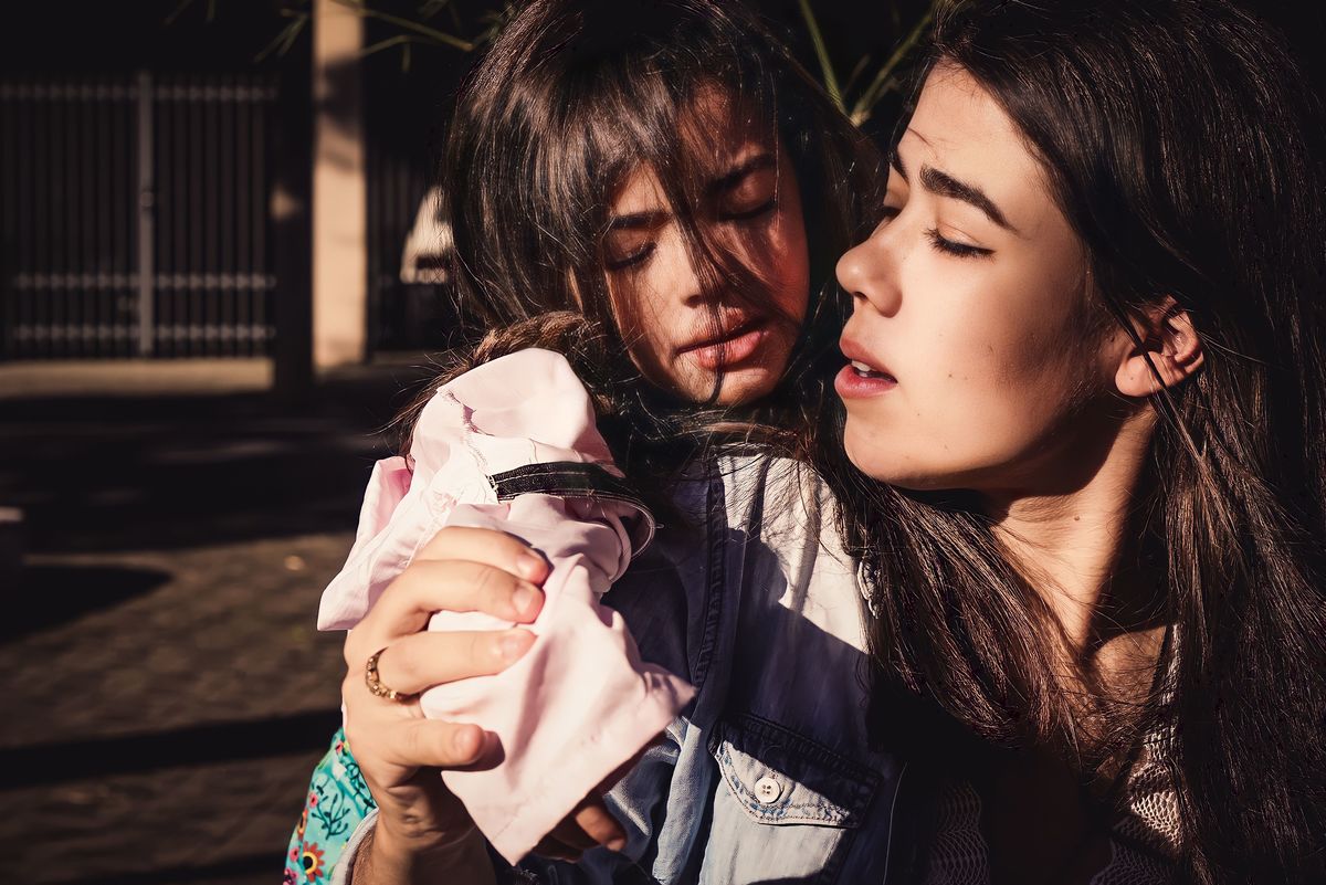 fotografia da filha da gestante abraçando ela por trás