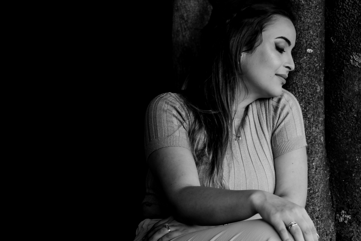 Retrato preto e branco de mulher escorada em uma árvore relaxando 