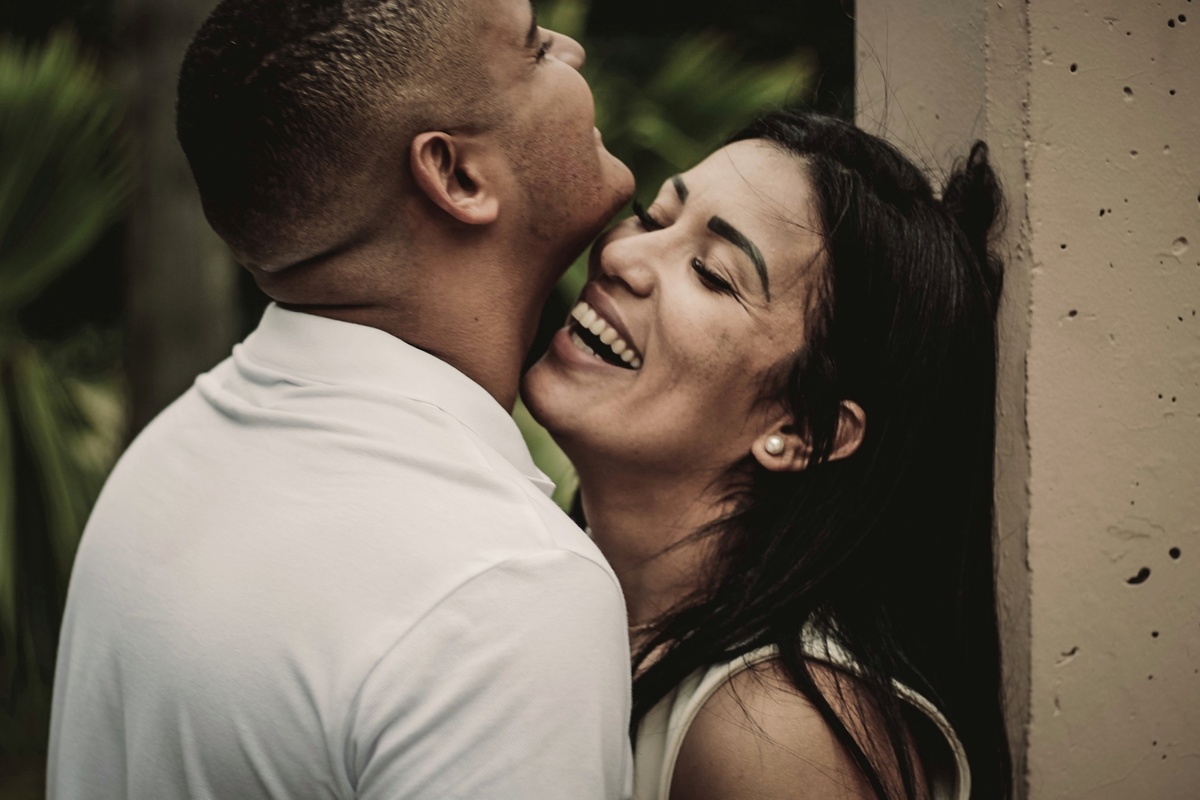 retrato da noiva encostada na parede enquanto eles se abraçam e dão risada