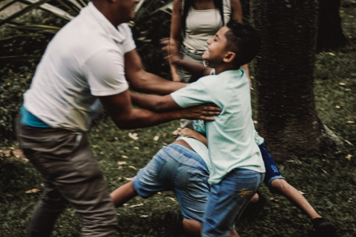 fotografia das crianças brincando de lutinha com seu pai