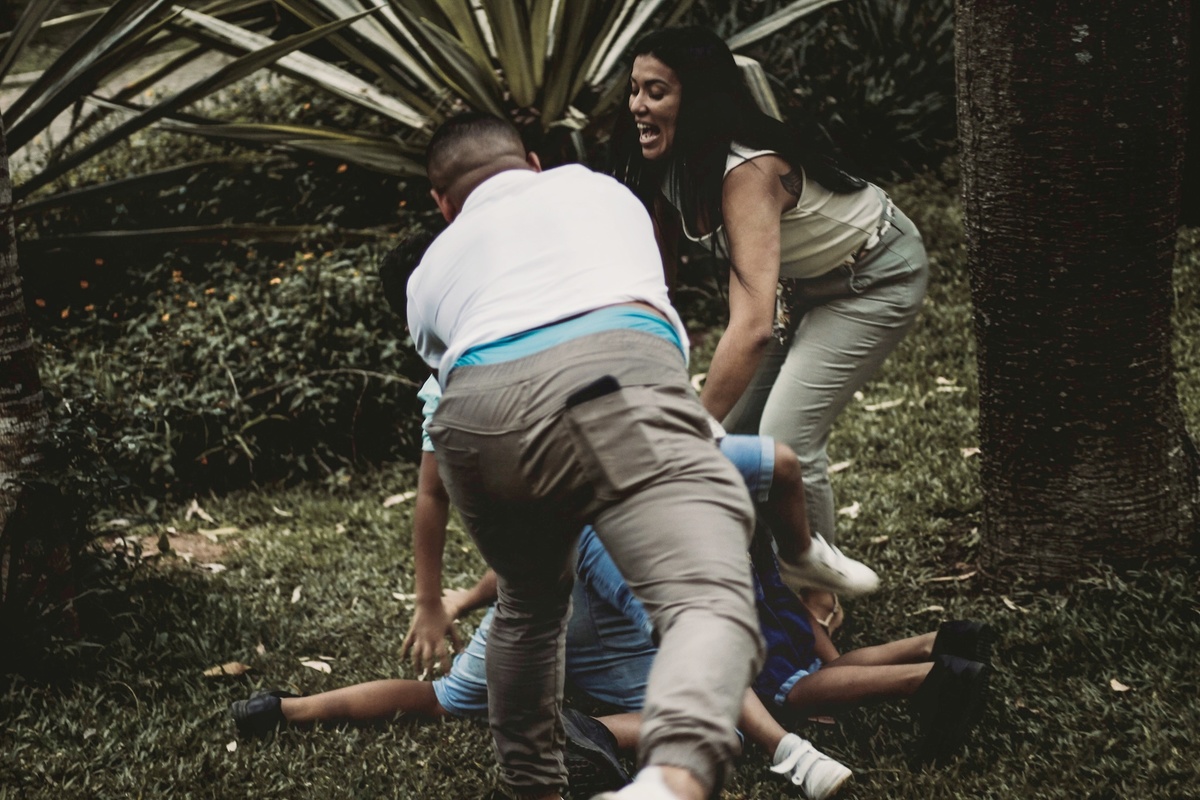 fotografia do pai derrubando seus filhos na grama