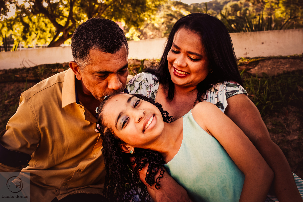 retrato da fília no colo dos pais e seu pai beijjando a cabeça da filha