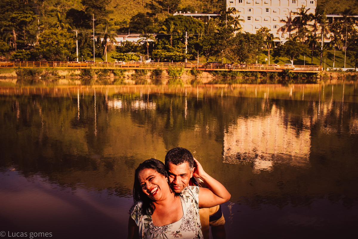 fotografia do marido abraçando a esposa com um lago enorme no fundo