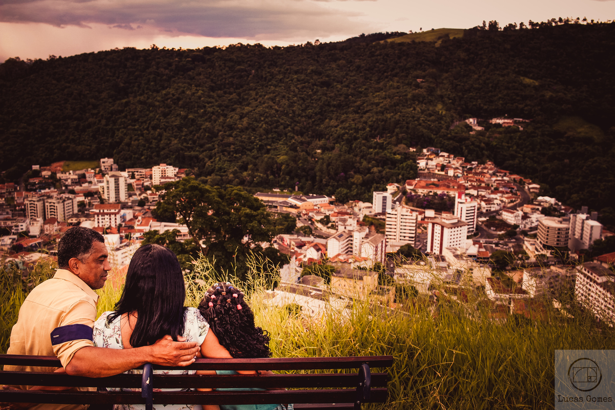 fotografia de familia sentada em um banco admirando uma paisagem do alto de um morro