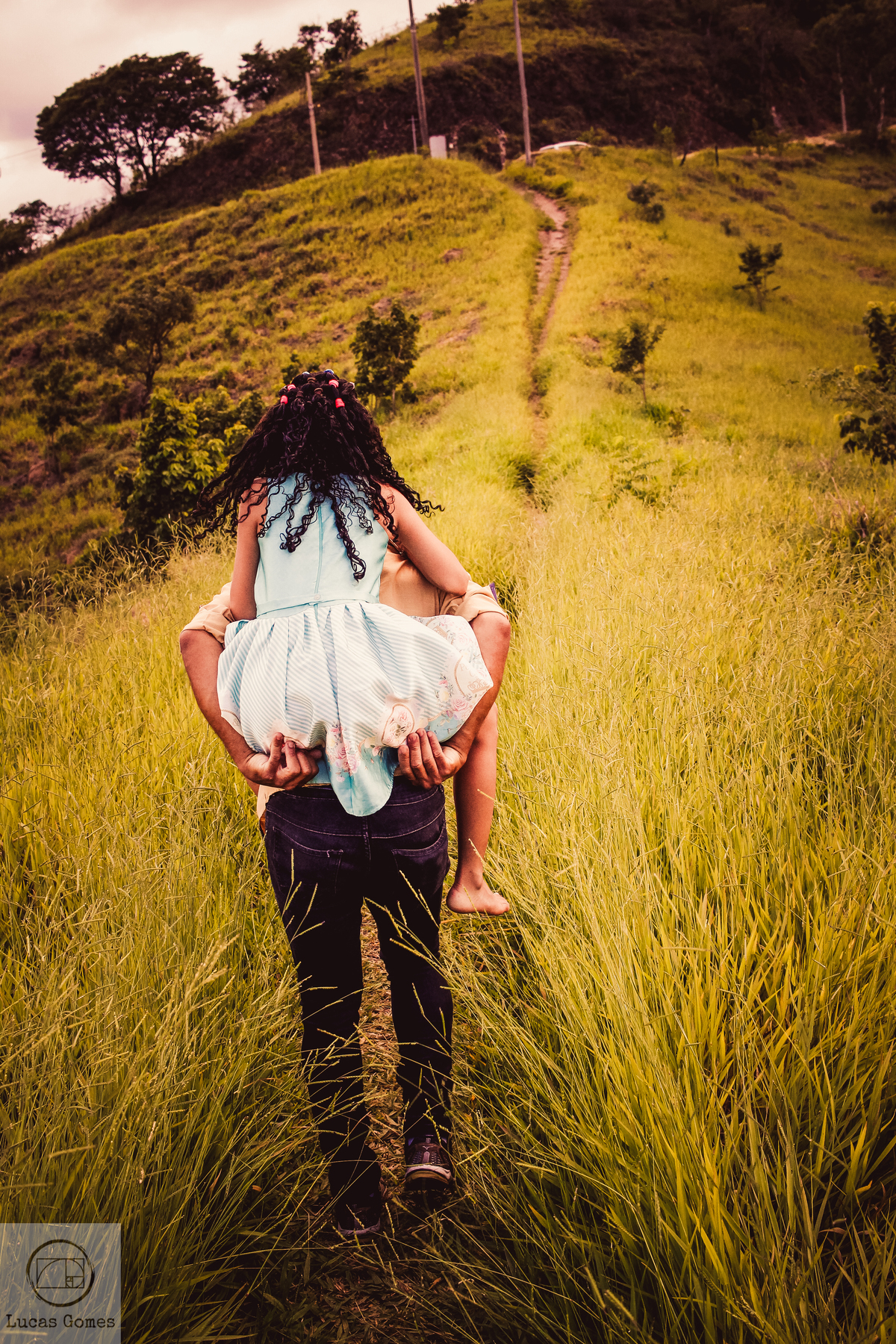 fotografia de pai carregando sua filha nas costas para subir o morrinho