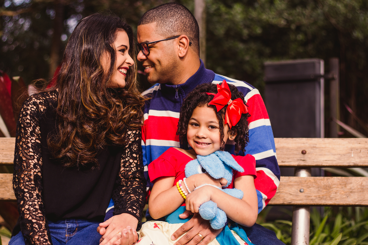 família sentada no banco, menina com coelhinho da Monica nos braços