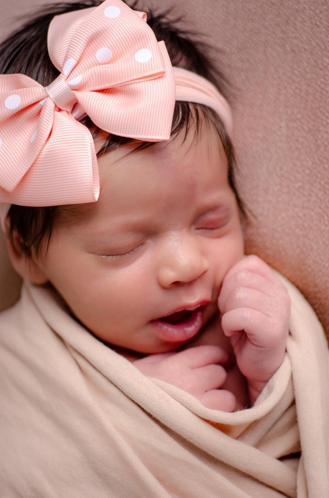 foto close bebe menina dormindo newborn enrolada wrap laço rosa