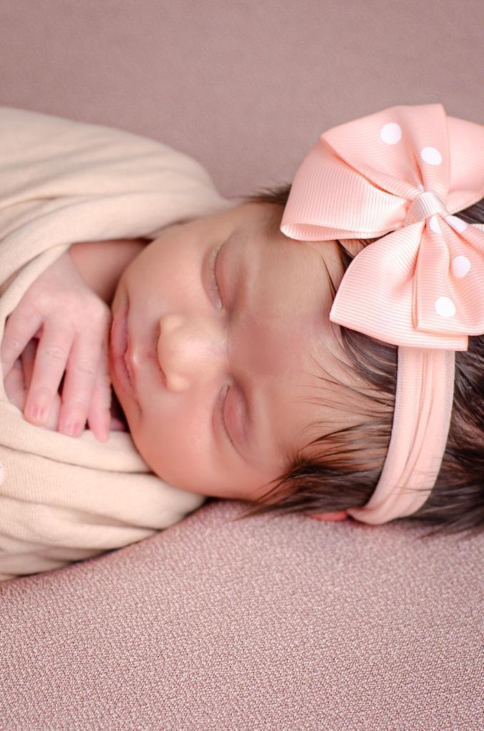 foto close bebe menina dormindo newborn enrolada wrap laço rosa