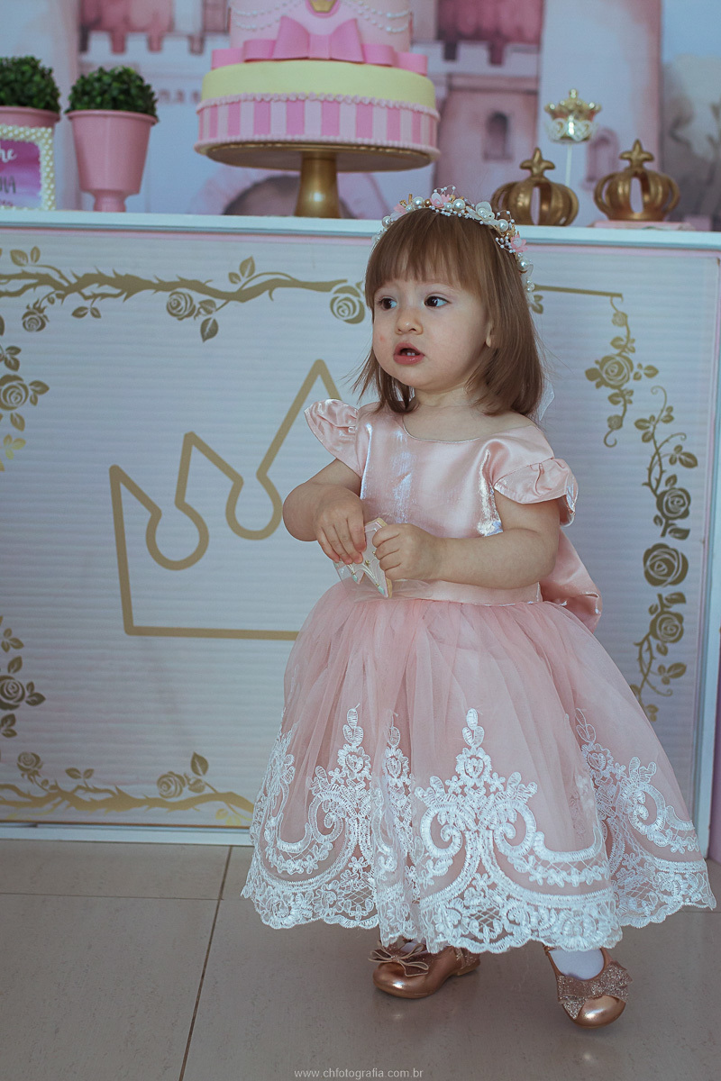 Retrato da aniversariante usando vestido de princesa durante sua festa de aniversário infantil.