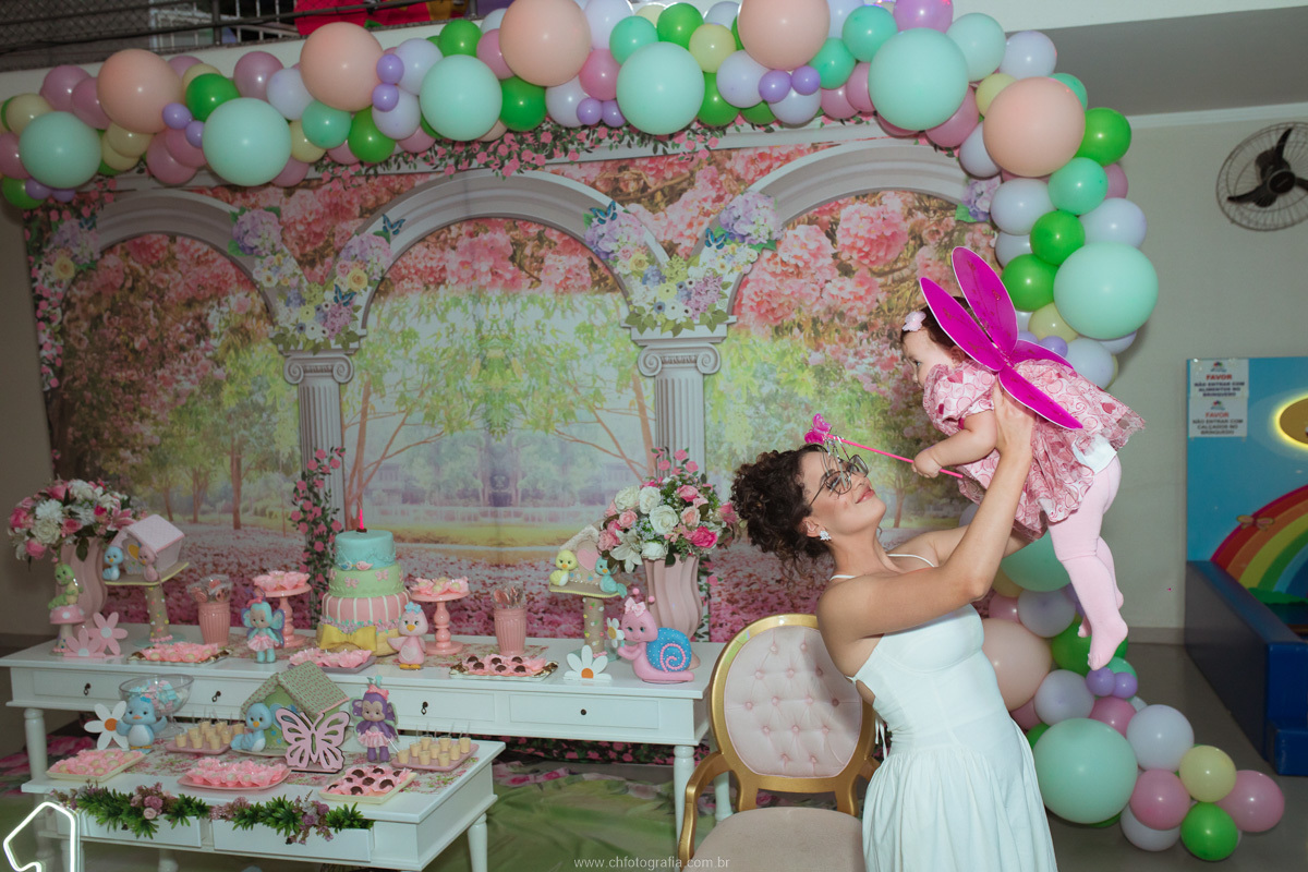 Fotografia espontânea da mãe abraçando a filha durante a comemoração do aniversário infantil.