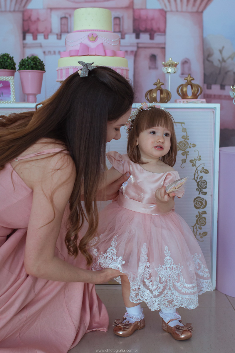 Fotografia da mãe com a filha durante o aniversário infantil, eternizando um momento de carinho e felicidade.