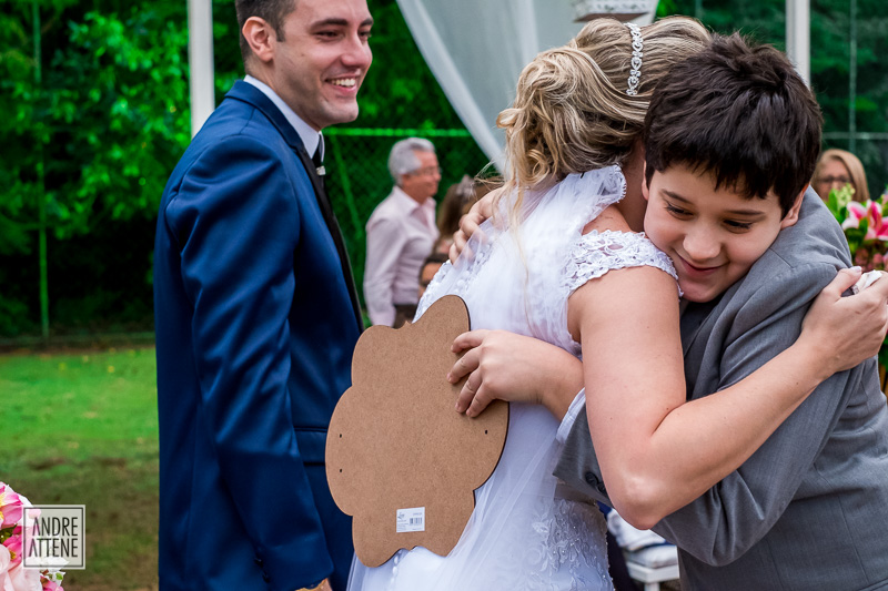 criança com placa abraça a noiva em seu casamento