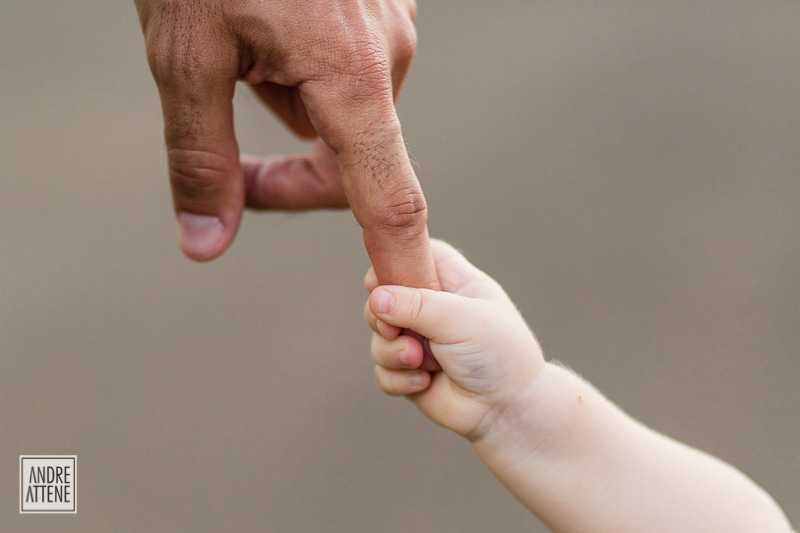 detalhe da mãozinha da criança segurando a mão do pai
