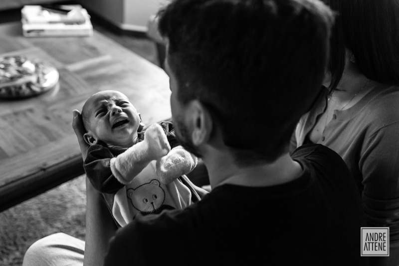 fotografia de família registra o chorinho do bebê e seu pai o confortando