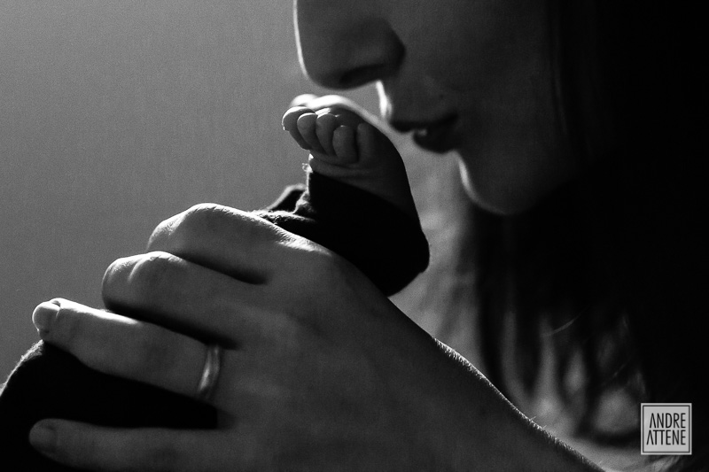 mamãe beijando o pezinho de seu filho delicadamente em fotografia de família de Andre Attene