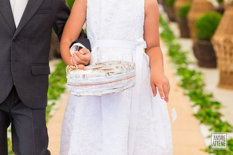 detalhe das mãos da florista jogando as pétalas que preparam o caminho da noiva para o altar em fotografia de Andre Attene