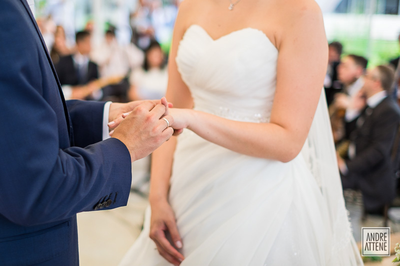detalhe mostra noivo colocando a aliança em sua noiva durante sua cerimônia de casamento fotografada por Andre Attene, fotógrafo em São Paulo