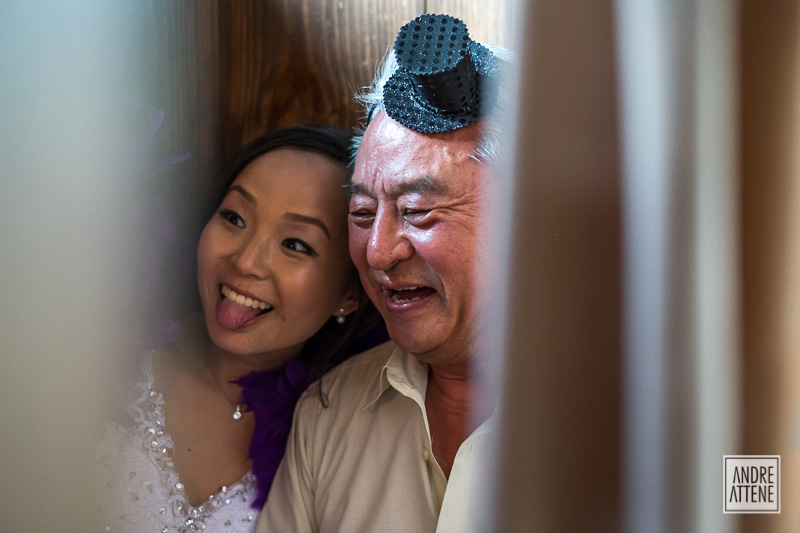 noiva Janete com seu pai se divertem fazendo caretas em cabine de fotos na festa de seu casamento