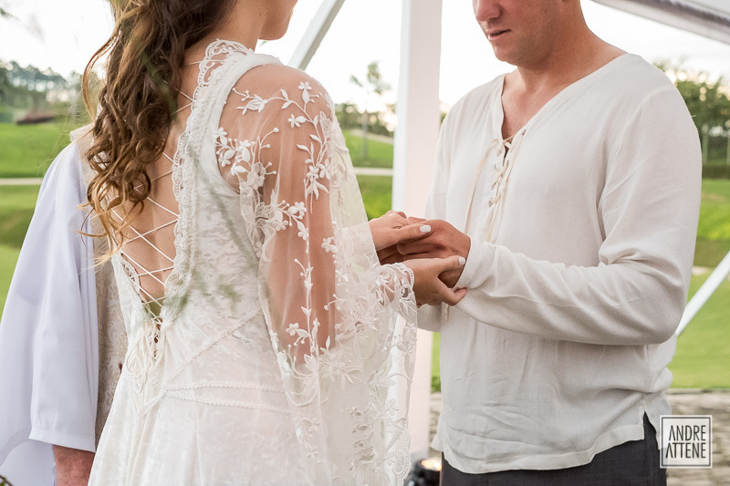 As mão dos noivos se seguram com firmeza, mas de forma natural e espontânea