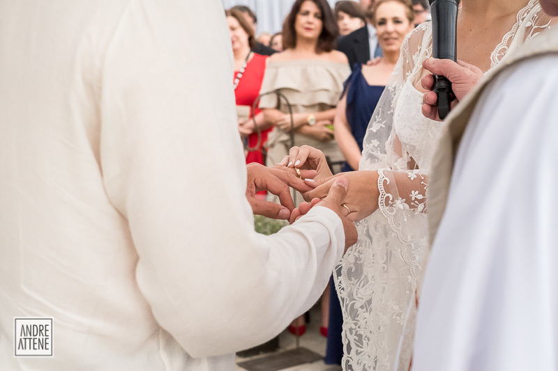 a noiva coloca a aliança no dedo de seu noivo em fotografia de Andre Attene