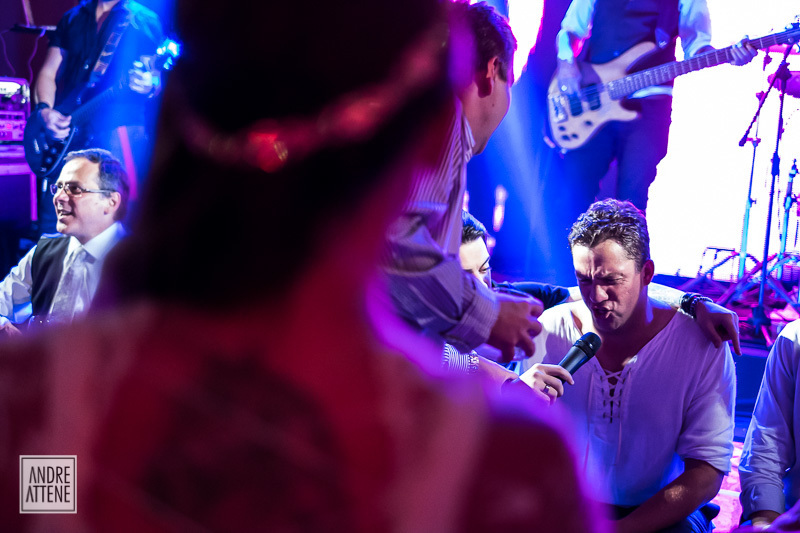 Noivo pega o microfone e canta para a noiva, que assiste encantada em sua festa de casamento