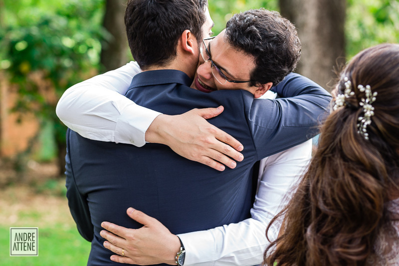 irmão do noivo o abraça emocionado ao se despedir no momento dos cumprimentos. Fotografia espontânea de Andre Attene
