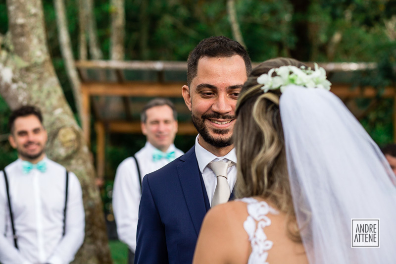 O noivo e os padrinhos sorriem em foto natural de Andre Attene