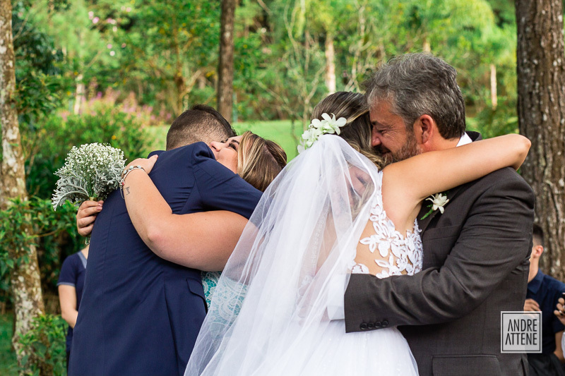 O pai da noiva a abraça carinhosamente