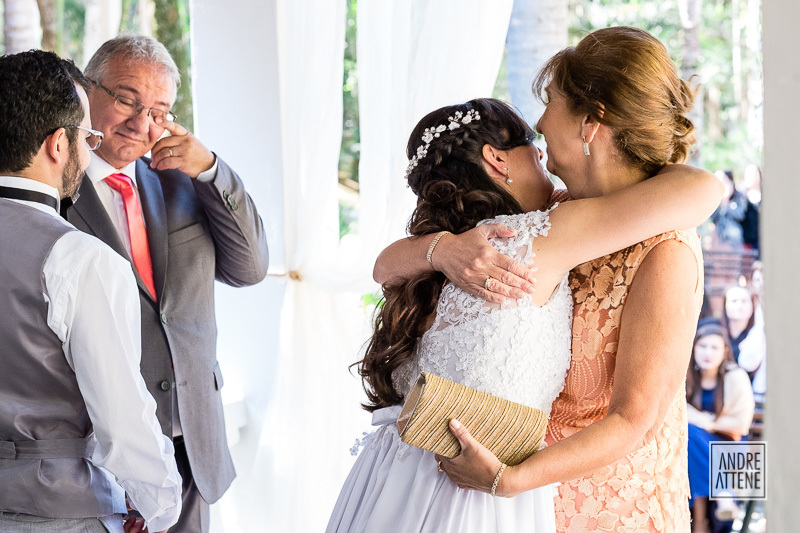 com muita emoção nesta fotografia de casamento espontânea, os pais da noiva cumprimentam os noivos