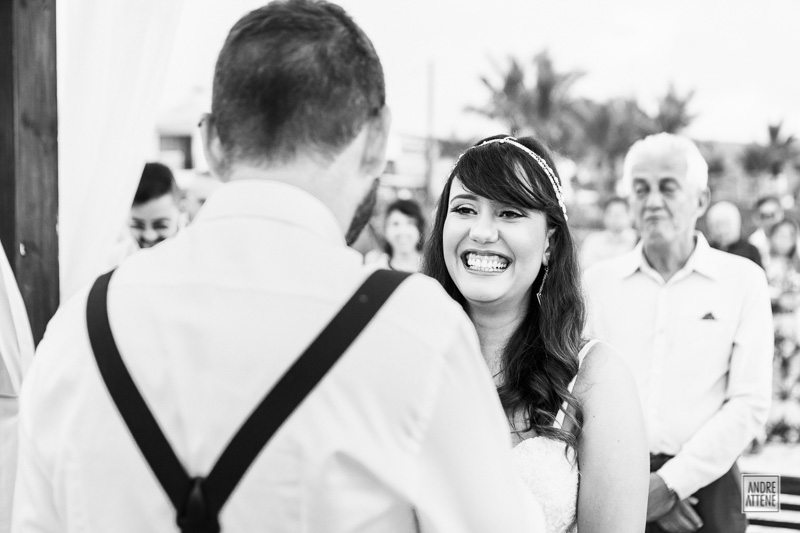 sorriso espontâneo da noiva olhando para o noivo em sua cerimônia de casamento na praia fotografada por Andre Attene de SP