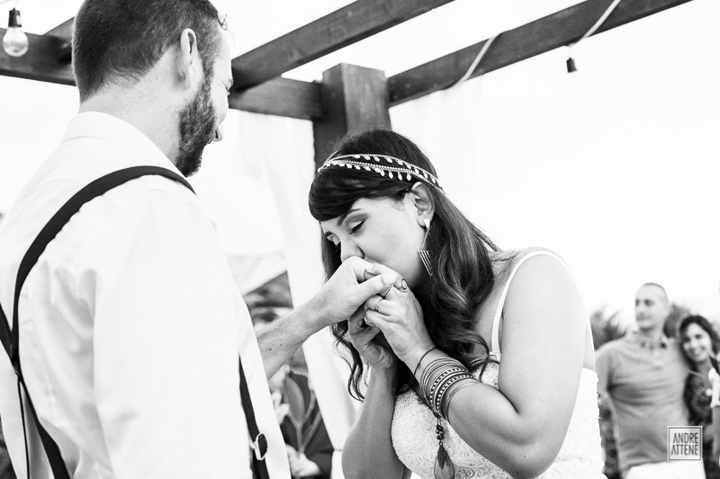 a noiva beija carinhosa a mão do noivo com sua aliança no casamento na praia registrado pelo fotógrafo de casamentos Andre Attene de SP