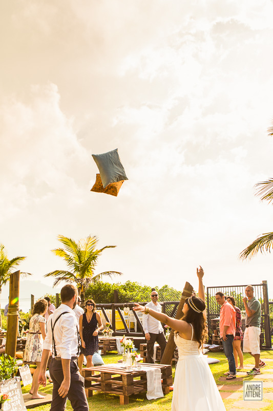 noiva se junta aos convidados que jogavam almofadas para o alto durante festa de casamento na praia fotografados por Andre Attene