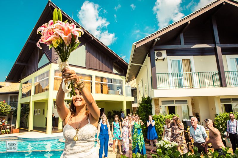 noiva prepara para jogar seu bouquet durante sua festa de casamento na praia fotografado por Andre Attene