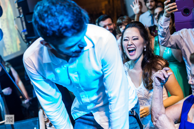 noiva animada e feliz com o noivo no palco durante festa de casamento fotografada por Andre Attene SP
