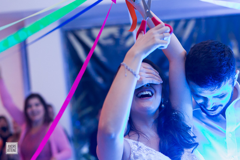 noivo tapa os olhos da noiva durante corte das fitas do bouquet de noiva em festa de casamento fotografado por Andre Attene