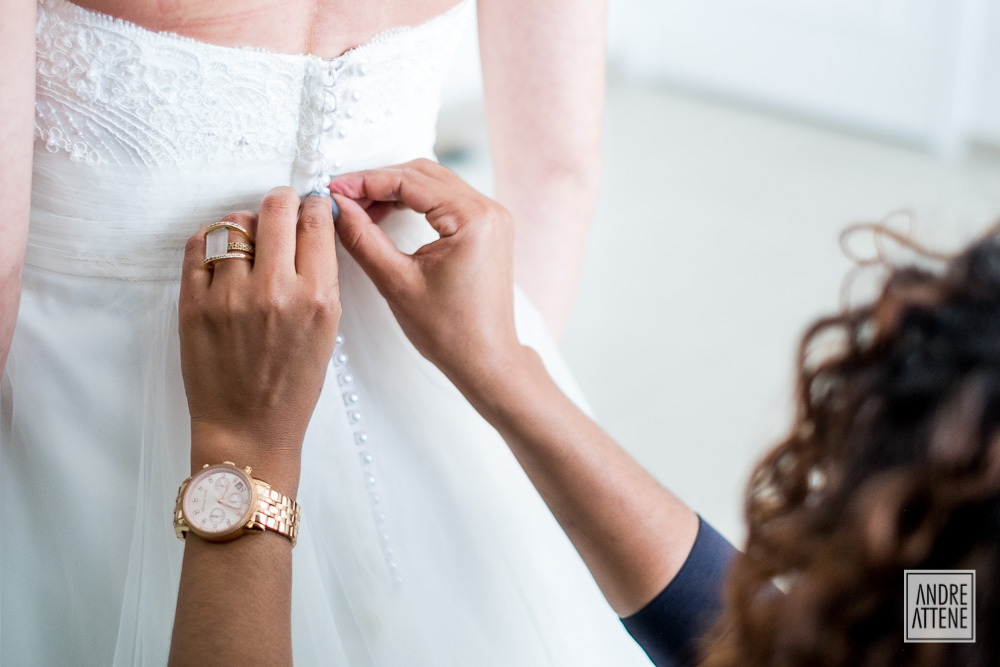 detalhe do vestido da noiva sendo fechado em fotografia de Andre Attene