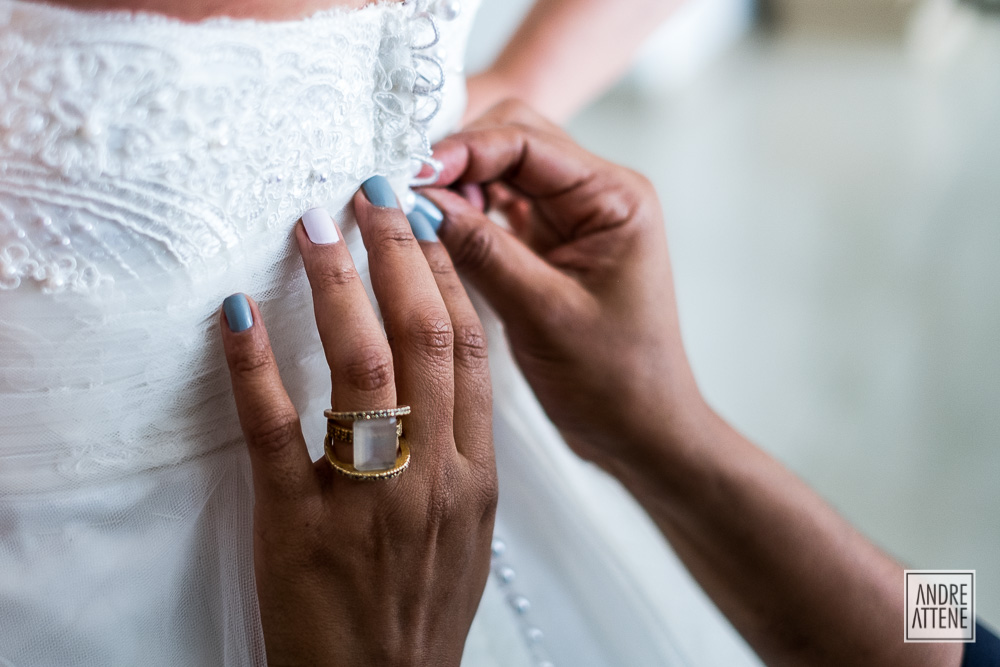 detalhe em close do vestido da noiva sendo abotoado em fotografia de Andre Attene em São Paulo