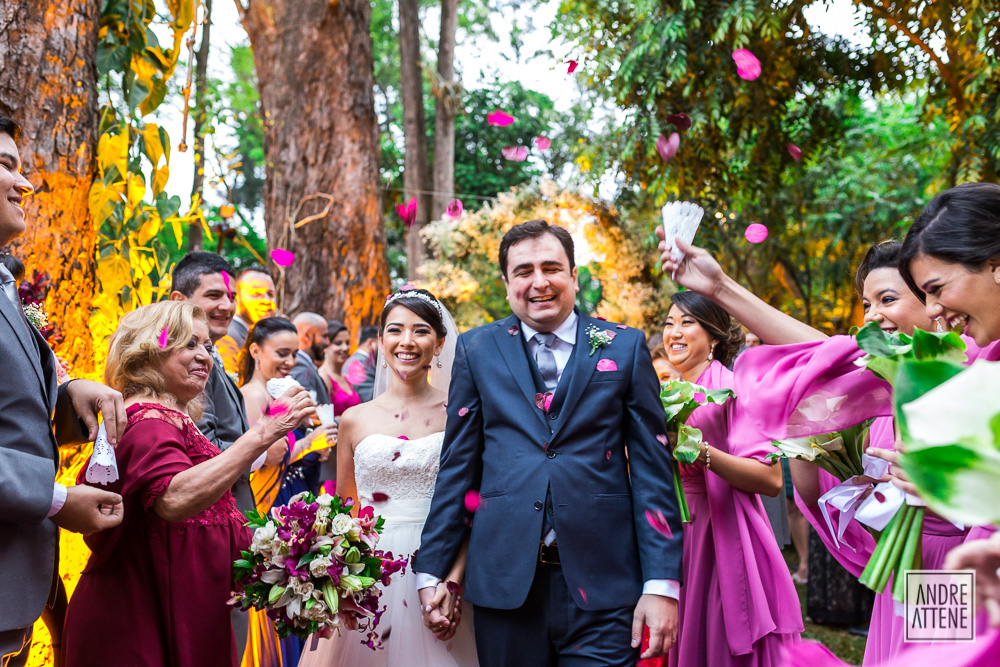 noivos saem com pétalas rosas comemorando o casamento em fotografia de Andre Attene
