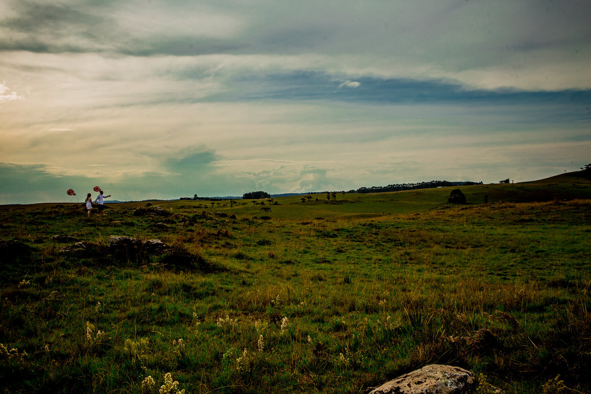 Fotógrafo de casamento de Cachoeirinha fotografia ensaio pré casamento casal caminhado no campo segurando balões