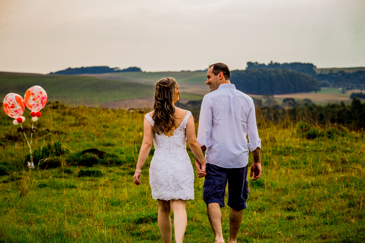 Fotógrafo de casamento de Cachoeirinha fotografia ensaio pré casamento casal caminhado de mãos dadas de costas com balões ao lado