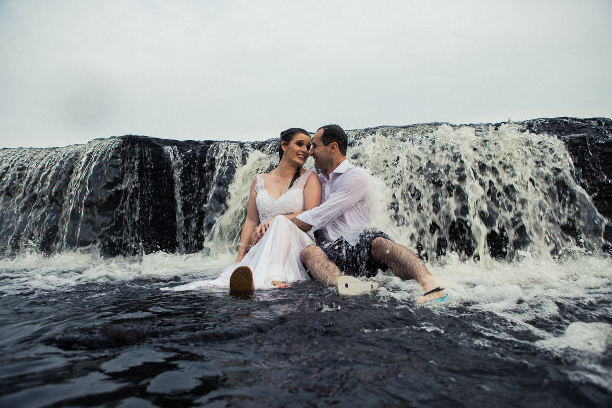 Fotógrafo de casamento de Cachoeirinha fotografia ensaio pré casamento casal sentado na pedra em frente a cachoeirinha se olhando