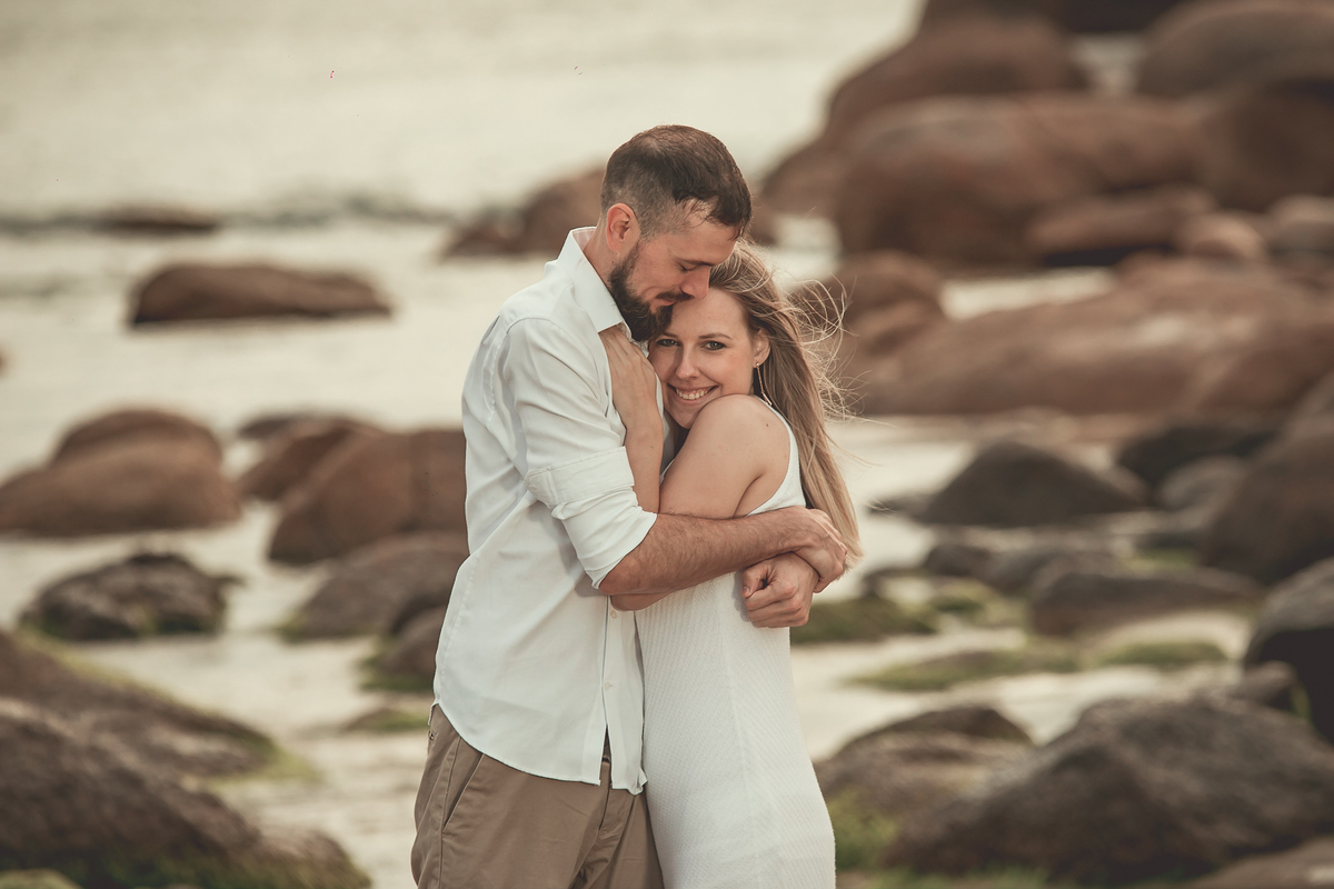 Fotógrafo de casamento de Cachoeirinha fotografia ensaio pré casamento casal abraçado e ao fundo mar e pedras