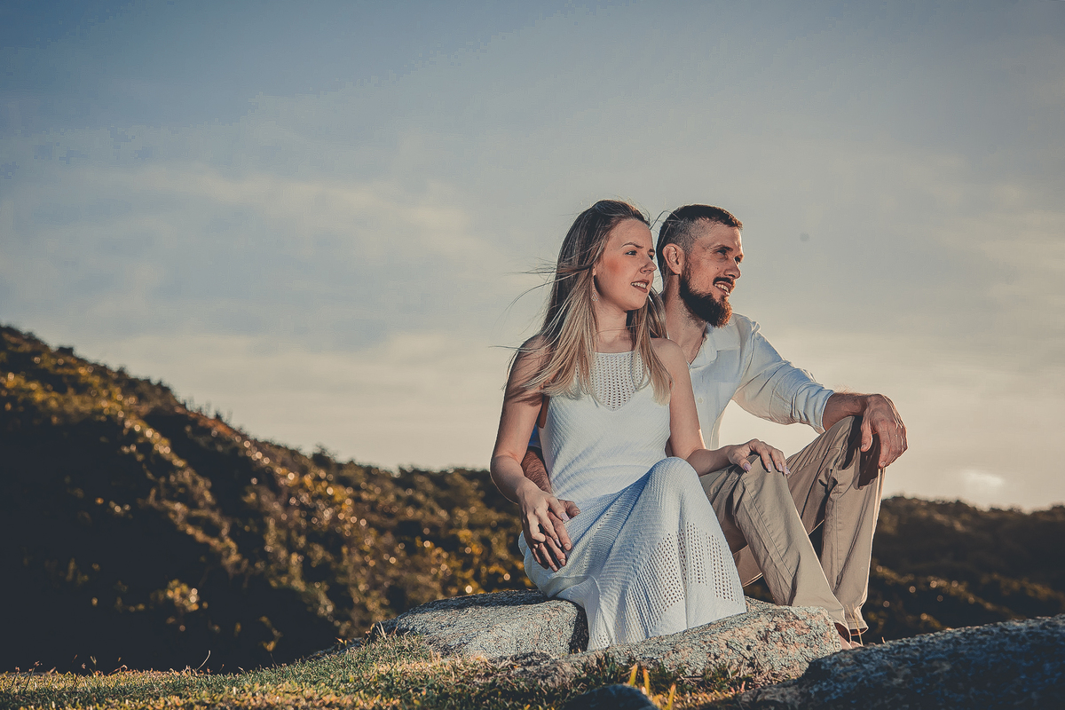 Fotógrafo de casamento de Cachoeirinha fotografia ensaio pré casamento casal sentado nas pedras no morro olhando para o horizonte
