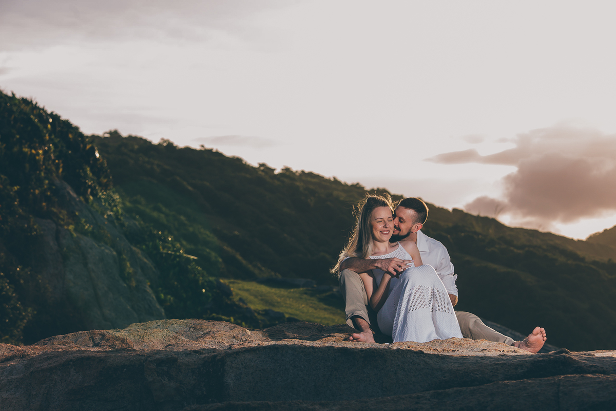 Fotógrafo de casamento de Cachoeirinha fotografia ensaio pré casamento casal sentado nas pedras no morro ele beijando ela