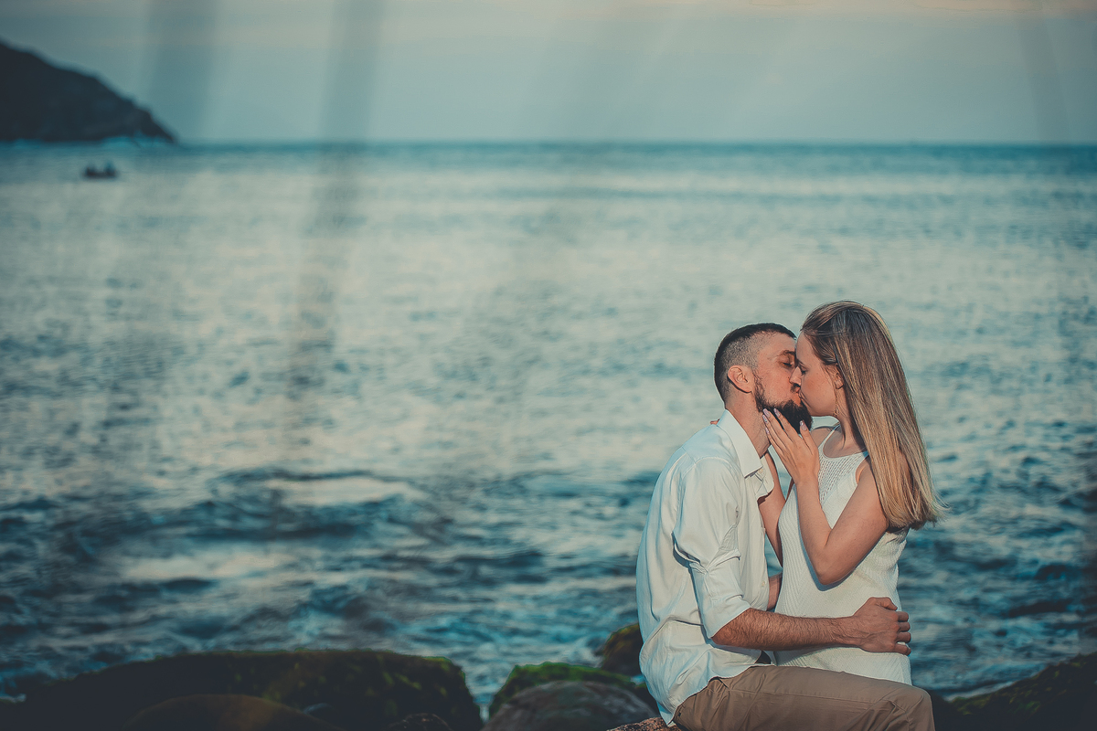 Fotógrafo de casamento de Cachoeirinha fotografia ensaio pré casamento casal se beijando sentado nas pedras e o mar ao fundo