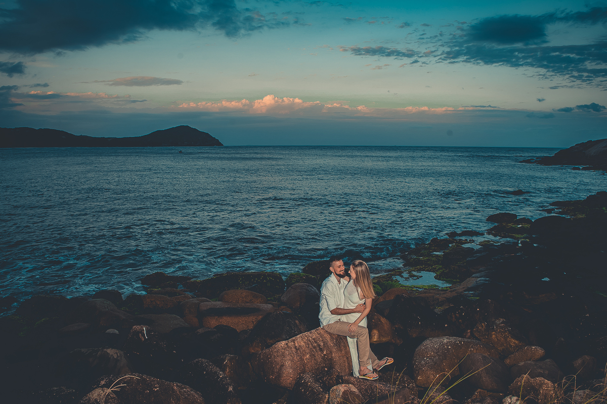 Fotógrafo de casamento de Cachoeirinha fotografia ensaio pré casamento casal se olhando sentado nas pedras e o mar ao fundo