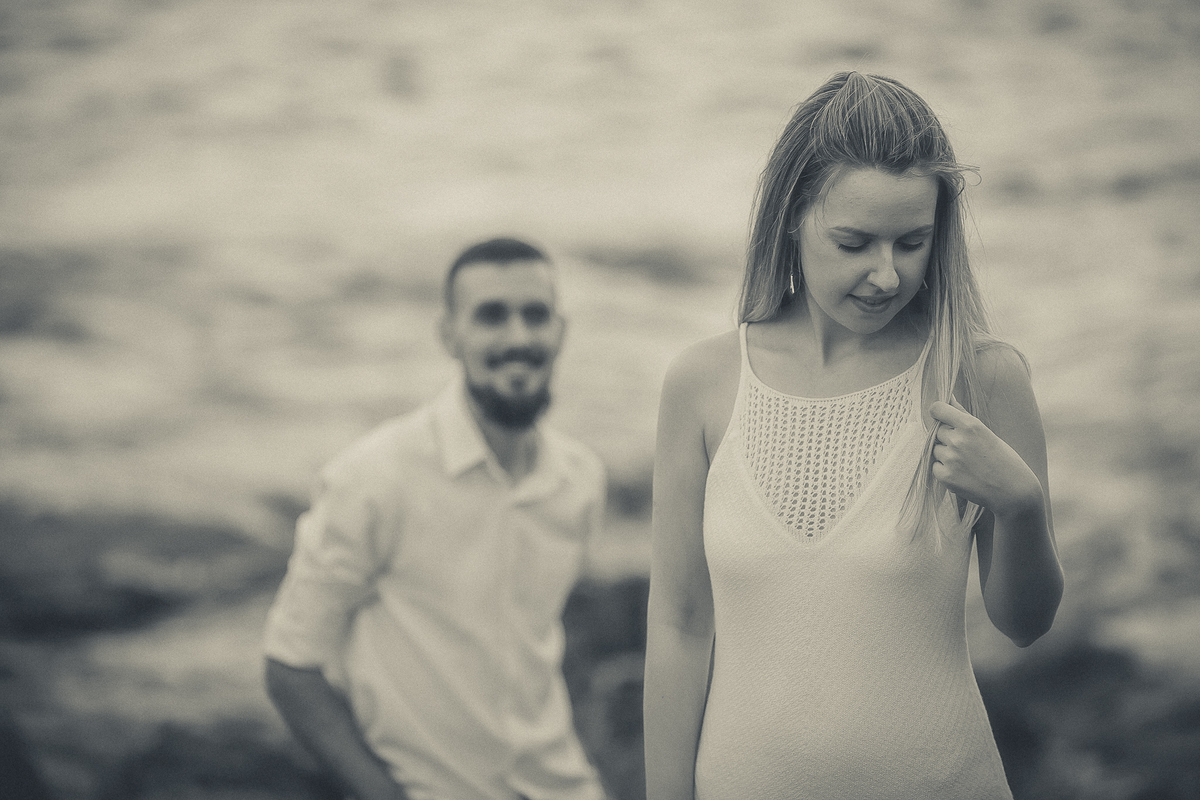 Fotógrafo de casamento de Cachoeirinha fotografia ensaio pré casamento ele ao fundo olhando para ela em destaque na frente preto e branco