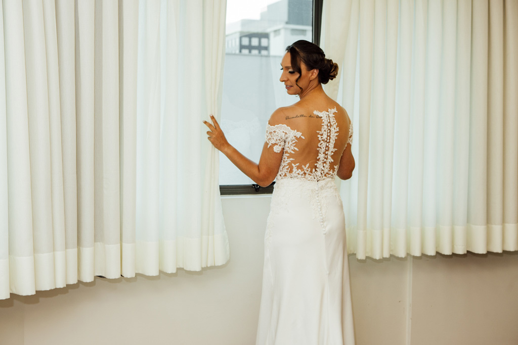 fotógrafo de casamento em cachoeirinha e porto alegre fotografia da noiva vestida de pé em frente de uma janela